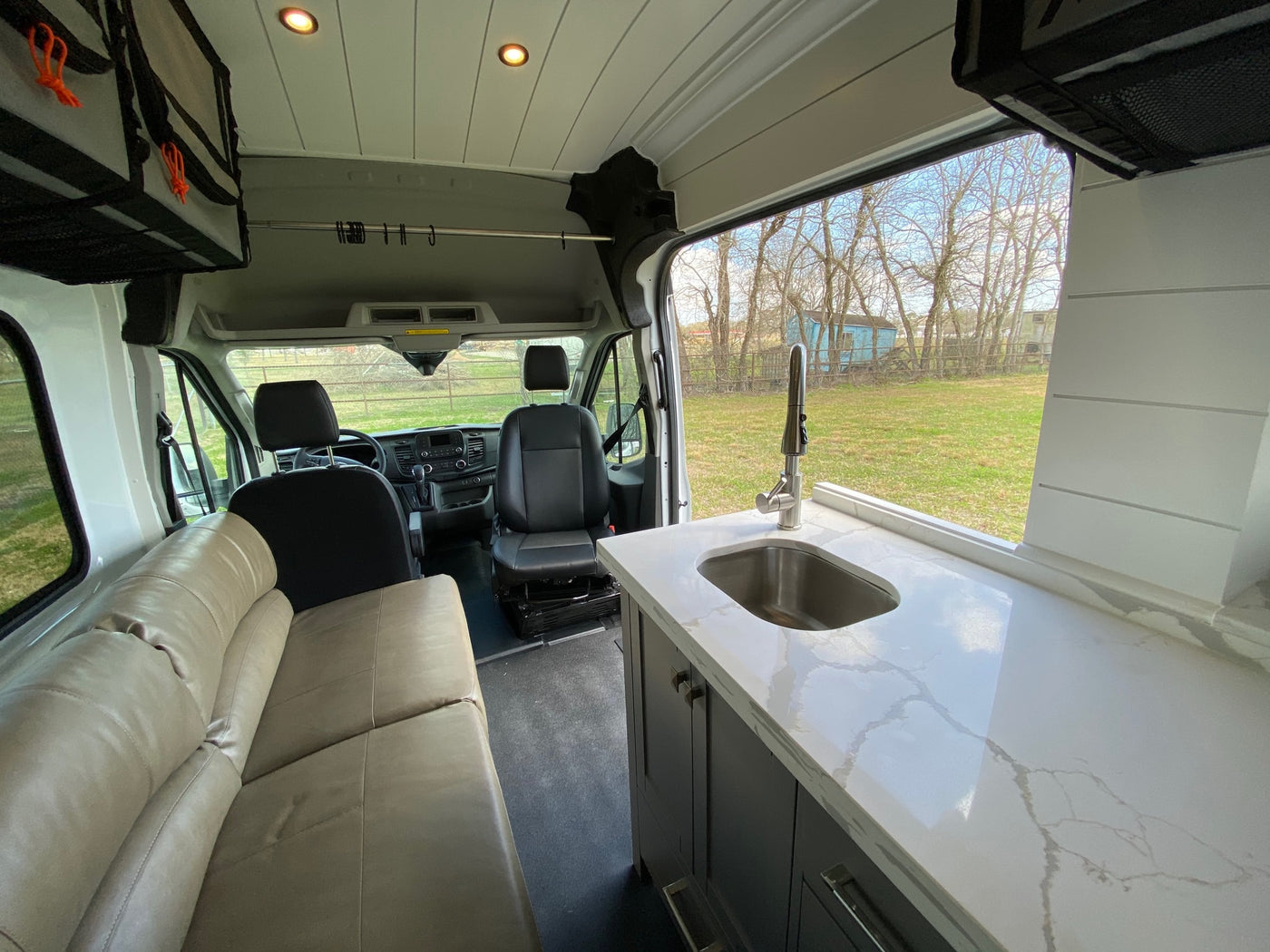 Spacious RV rental interior featuring a modern kitchenette with sink, comfortable lounge seating, and driver's cabin. — photo 2
