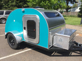 Explore with this vibrant teal & silver teardrop camper, an ideal rv rental. Features diamond plate accents, a side door, & front storage.