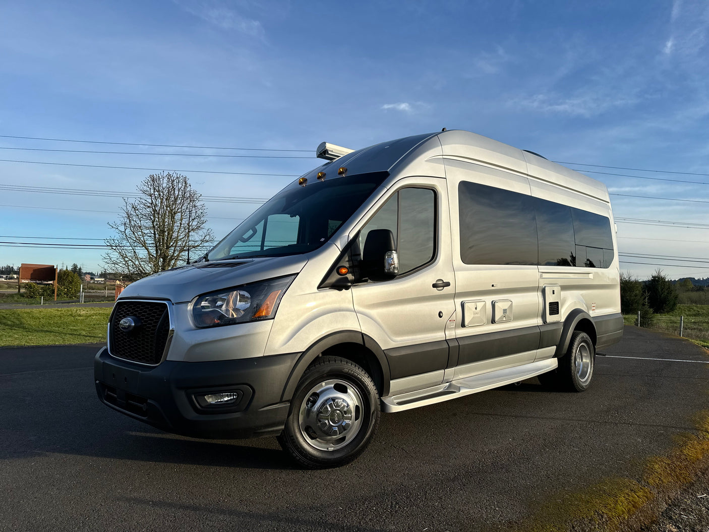 This silver Ford Transit camper van, an ideal RV rental, stands ready for scenic road trips and adventures.