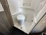 RV rental: Compact wet bath with toilet, shower, drain, and small shelf.