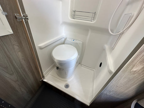 RV rental: Compact wet bath with toilet, shower, drain, and small shelf.