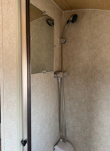 Step into this rv rental's compact shower: handheld shower, mirror, and light-patterned walls with wood ceiling.