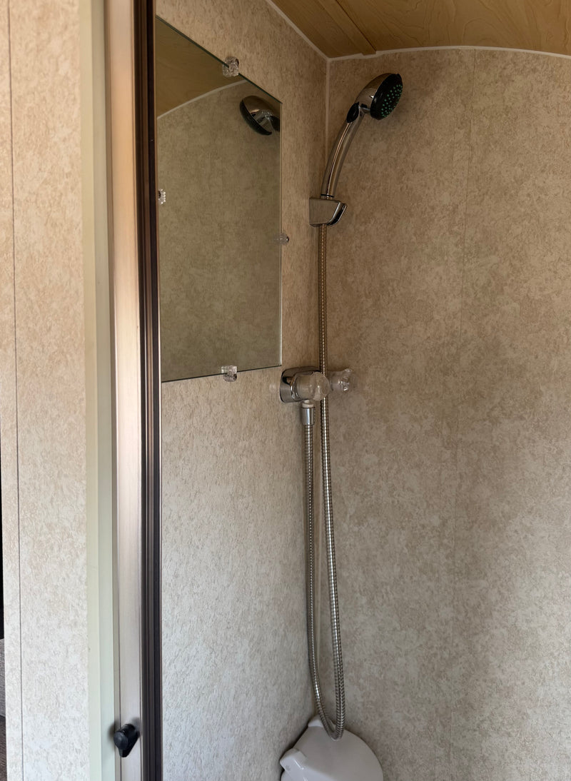 Step into this rv rental's compact shower: handheld shower, mirror, and light-patterned walls with wood ceiling. — photo 12
