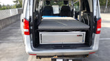 RV rental: Back of a camper van with a modular bed and pull-out TK Trail Kitchens unit, ideal for adventure & road trips.