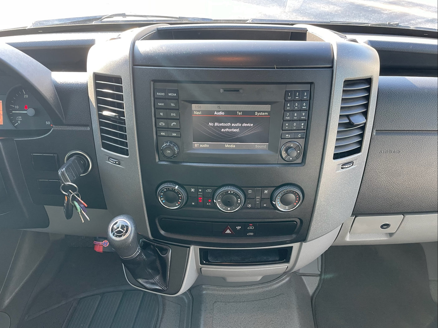 RV rental dashboard showing infotainment system with Bluetooth error, climate controls, gear shifter, and keys.