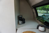 Inside a cozy RV rental: coffee station with Keurig, mug, frother, plus a plant by the window.