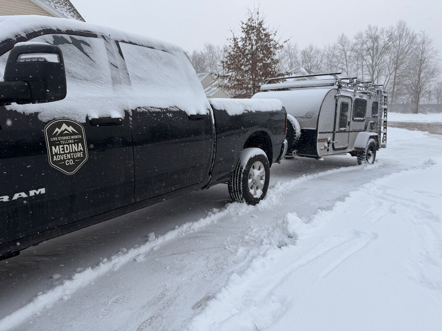 This black Ram pickup is hitched to a snowy RV rental teardrop trailer, ready for winter camping adventures.