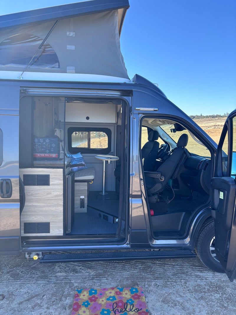 Explore inside this gray pop-top camper van RV rental! Side door open, showing inviting interior & outdoor scenery. — photo 7