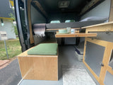 Inside this RV rental camper van: A versatile living space with cozy bed, bench seating, and a convenient pull-out table.