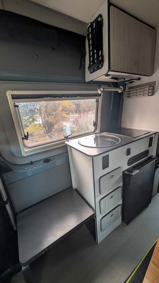  and swivel driver's seat.|Cozy RV rental interior with a small dining table set with two red plates and a cup — photo 9