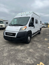 Front view of a white Winnebago Ram ProMaster RV rental van, featuring roof marker lights, parked on asphalt.