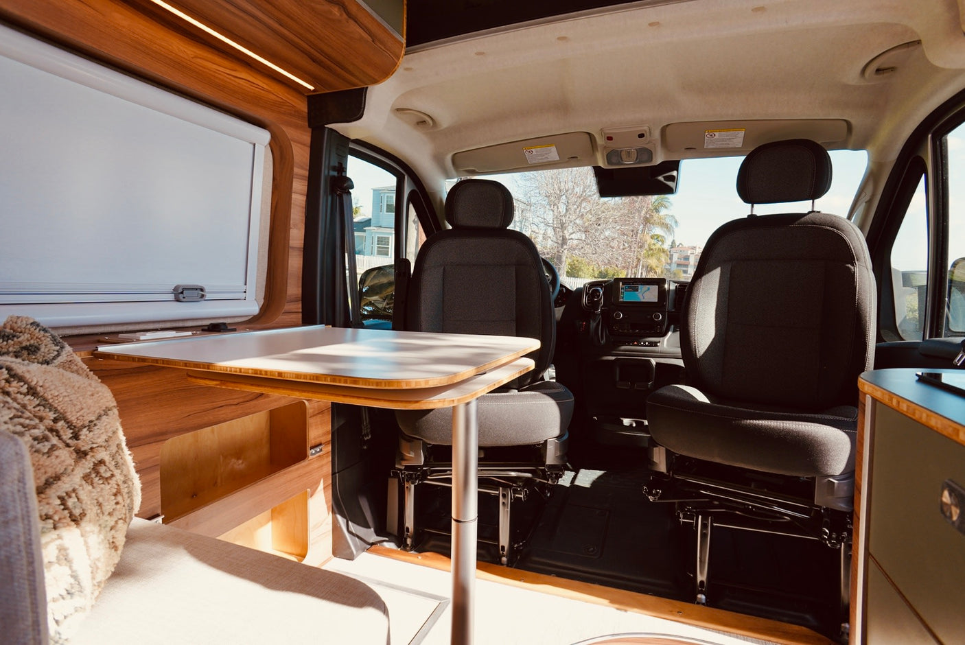 Modern RV rental interior showcasing swivel front seats, a dining table, and wood accents. Ready for road trips.