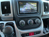RV rental dashboard with Pioneer backup camera showing a muddy path, climate controls, and gear shifter in Reverse.