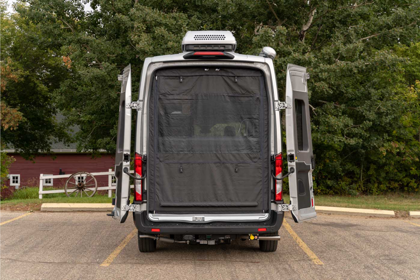 Rear view of a silver rv rental camper van with open doors and mesh screen, parked outdoors near a barn. — photo 15
