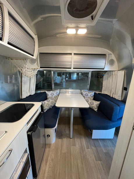 Clean RV rental interior featuring a bright dinette, compact kitchen, and organized overhead storage.