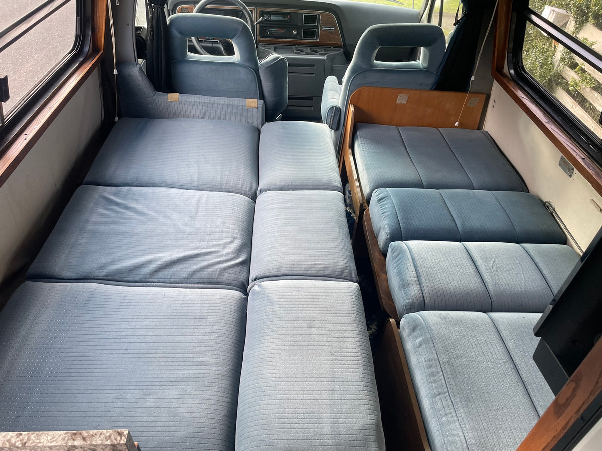 Inside a vintage RV rental: blue modular beds/seating fill this cozy camper van, ready for travel adventures. — photo 8