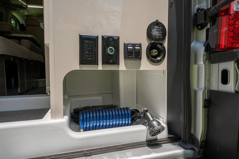 This RV rental's external utility bay provides an outdoor shower, power outlet, and water & light controls. — photo 20