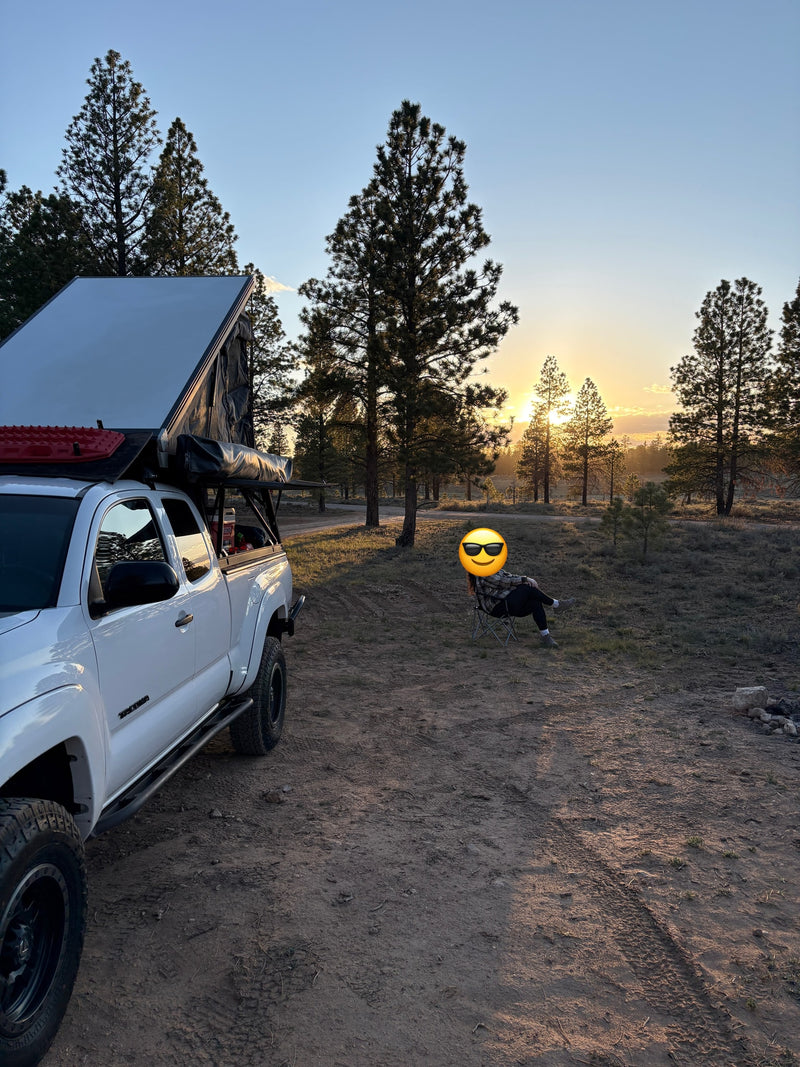 White pickup with rooftop tent & person enjoying sunset. Perfect for off-grid overlanding; a unique rv rental alternative. — photo 7