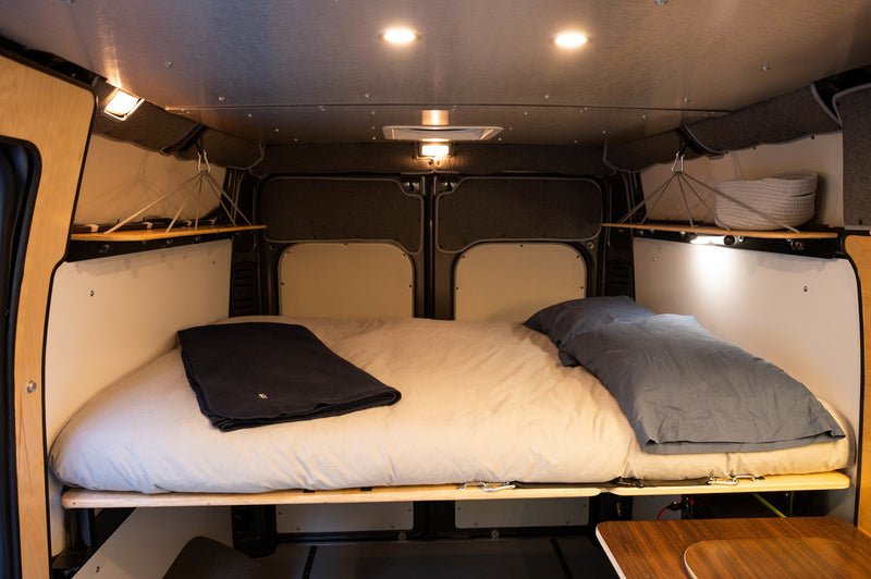 Inside this cozy RV rental: a spacious bed with bedding, ambient lighting, and clever storage, perfect for comfortable travel. — photo 6