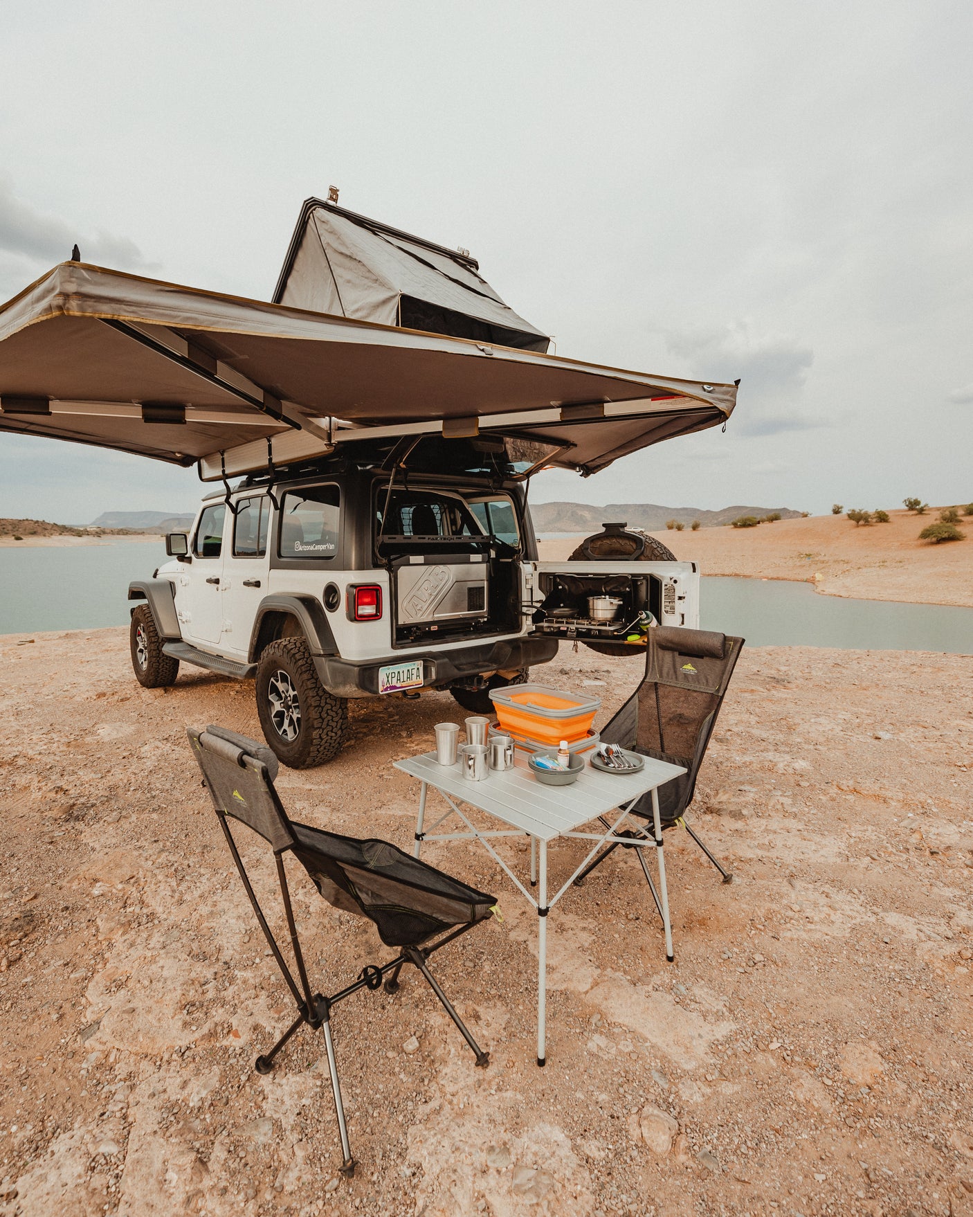 Experience outdoor adventure! This rv rental Jeep, equipped with a rooftop tent & camp kitchen, is ready for lakeside overlanding.