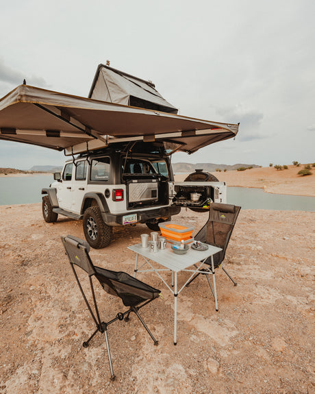 Experience outdoor adventure! This rv rental Jeep, equipped with a rooftop tent & camp kitchen, is ready for lakeside overlanding.