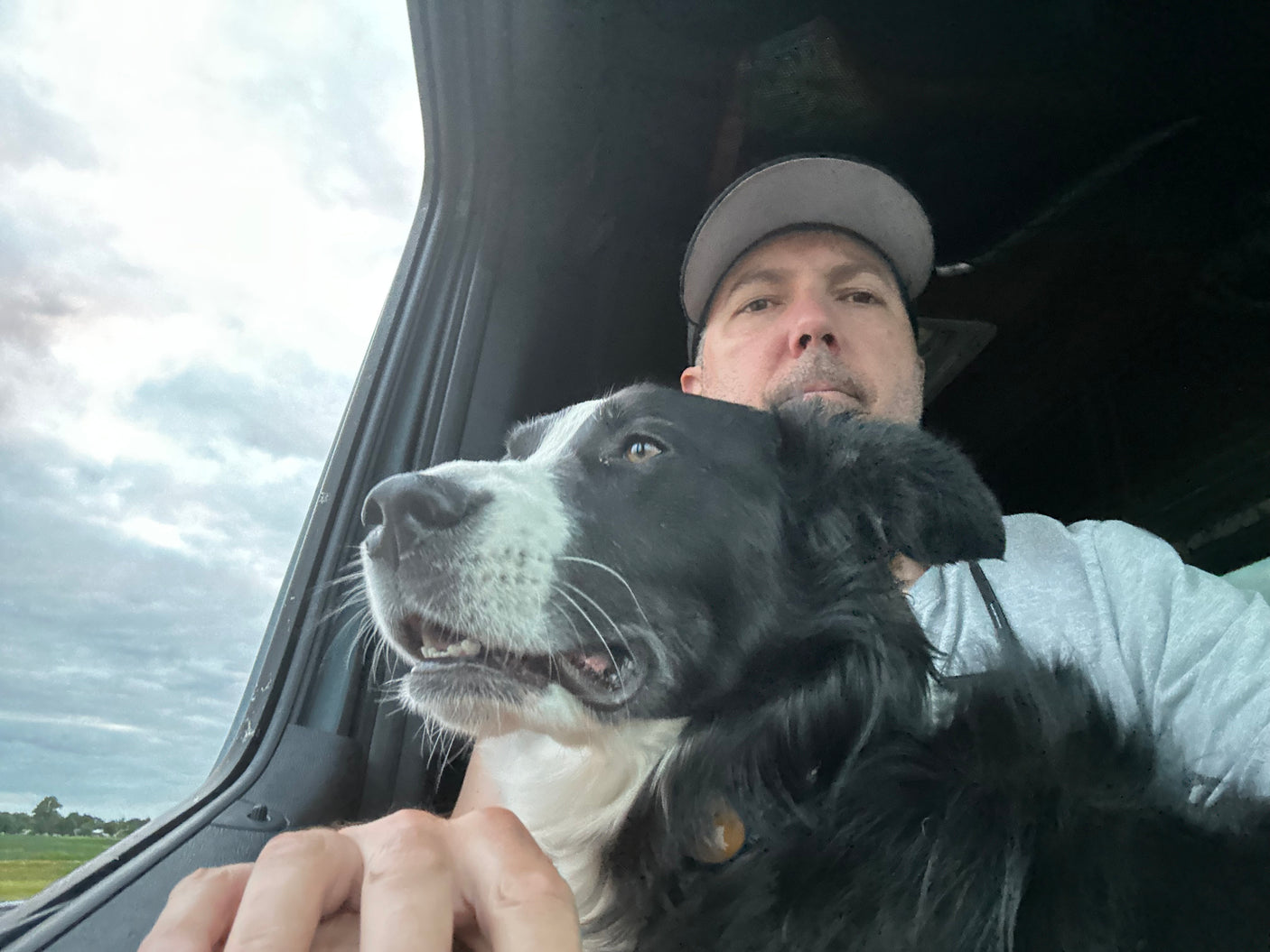 Travel buddy! Man and black & white dog enjoying the view from their RV rental window on a cloudy day. Adventure awaits.