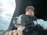 Travel buddy! Man and black & white dog enjoying the view from their RV rental window on a cloudy day. Adventure awaits.