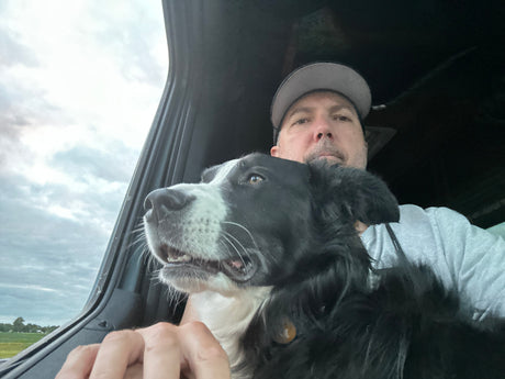 Travel buddy! Man and black & white dog enjoying the view from their RV rental window on a cloudy day. Adventure awaits.