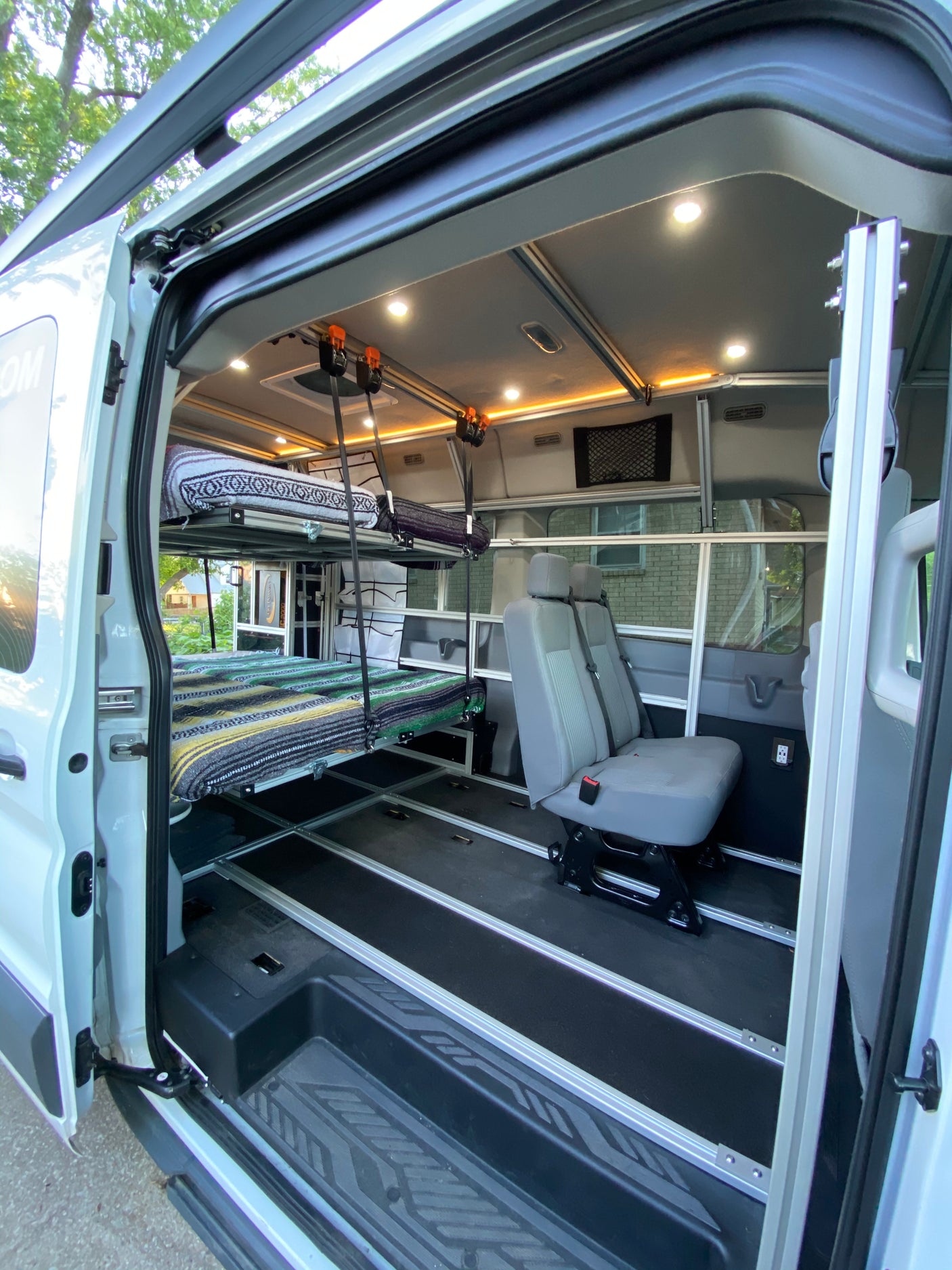 Spacious and adaptable RV rental interior with a modular bunk bed system, ample seating, and bright lighting.