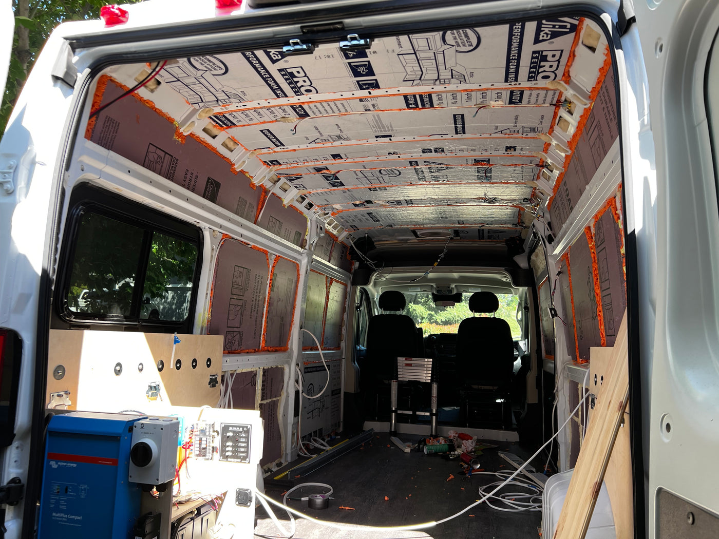 DIY van conversion for an **rv rental**, featuring exposed insulation, electrical setup, and the bare interior structure of the van. — photo 19