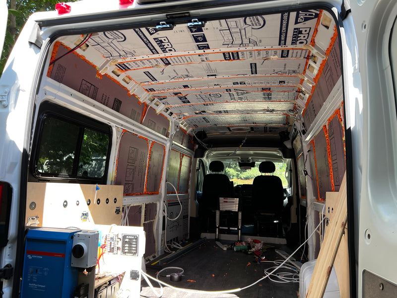 DIY van conversion for an **rv rental**, featuring exposed insulation, electrical setup, and the bare interior structure of the van. — photo 19