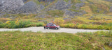 Maroon SUV on a dirt road in fall mountains, great for exploring. Consider an rv rental for similar scenic adventures!