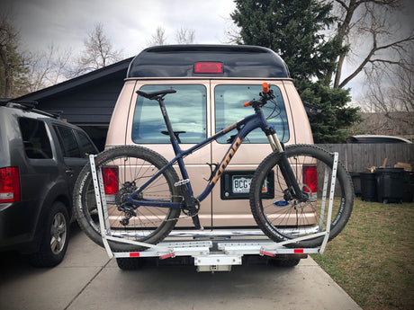 Tan RV rental with a Kona mountain bike on a hitch rack. Ready for off-road adventures!