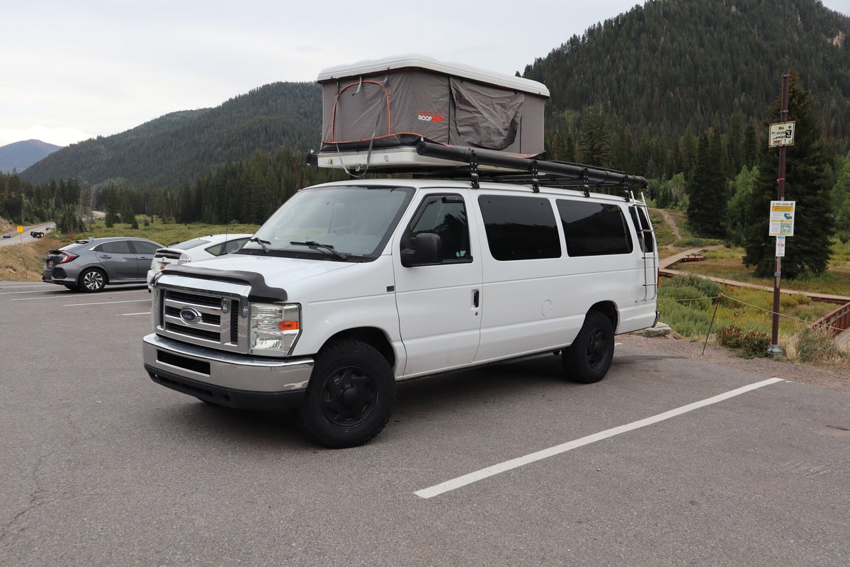 White RV rental camper van with rooftop tent, parked in a scenic mountain area. — photo 3
