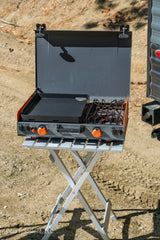 An RV rental must-have: A portable Blackstone griddle and stove on a folding table for outdoor campsite cooking.