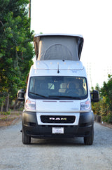 White RAM pop-top camper van, an rv rental, with its roof extended. Parked on asphalt, ready for outdoor adventures.