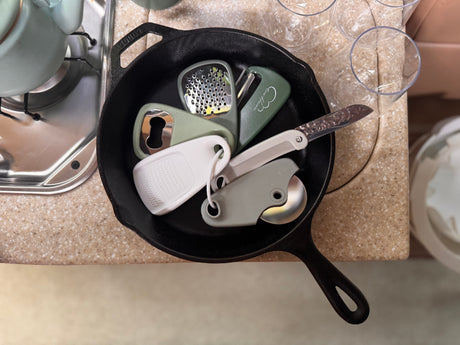 RV rental kitchen: A cast iron pan holds compact tools like a grater, peeler, knife, bottle opener, and pizza cutter.