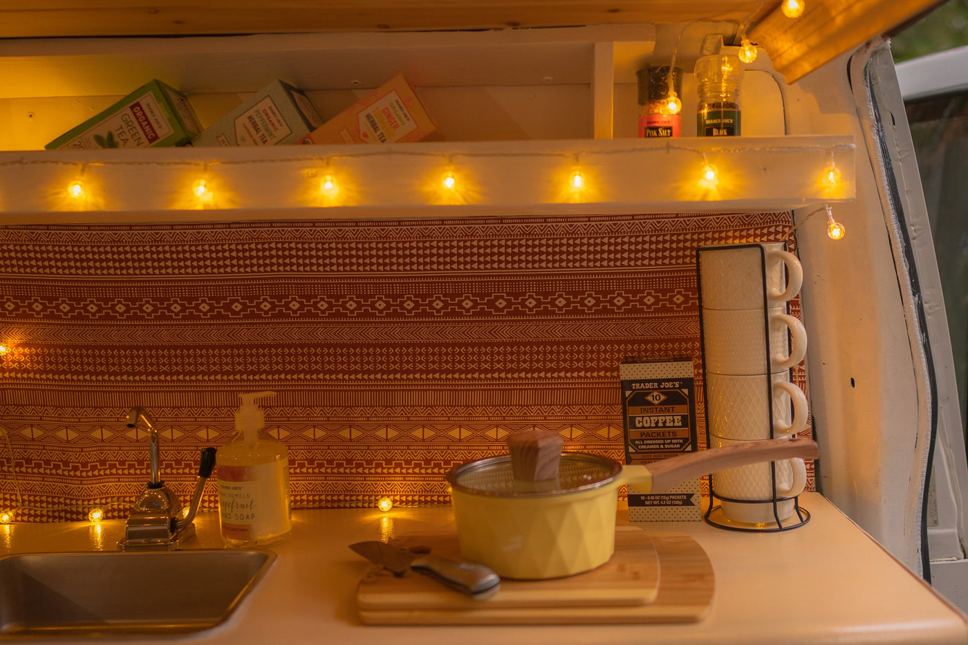 Warmly lit RV rental kitchen featuring Trader Joe's teas, spices, and coffee, a mini sink, and cooking essentials. — photo 8