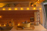 Warmly lit RV rental kitchen featuring Trader Joe's teas, spices, and coffee, a mini sink, and cooking essentials.
