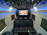 Spacious luxury rv rental interior featuring custom black seating, a large TV for football, and stylish blue LED lights.