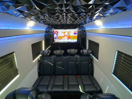 Spacious luxury rv rental interior featuring custom black seating, a large TV for football, and stylish blue LED lights.