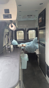 Inside this rv rental van: a well-equipped kitchenette, cozy blue bed, fridge, and overhead controls for comfy travels.