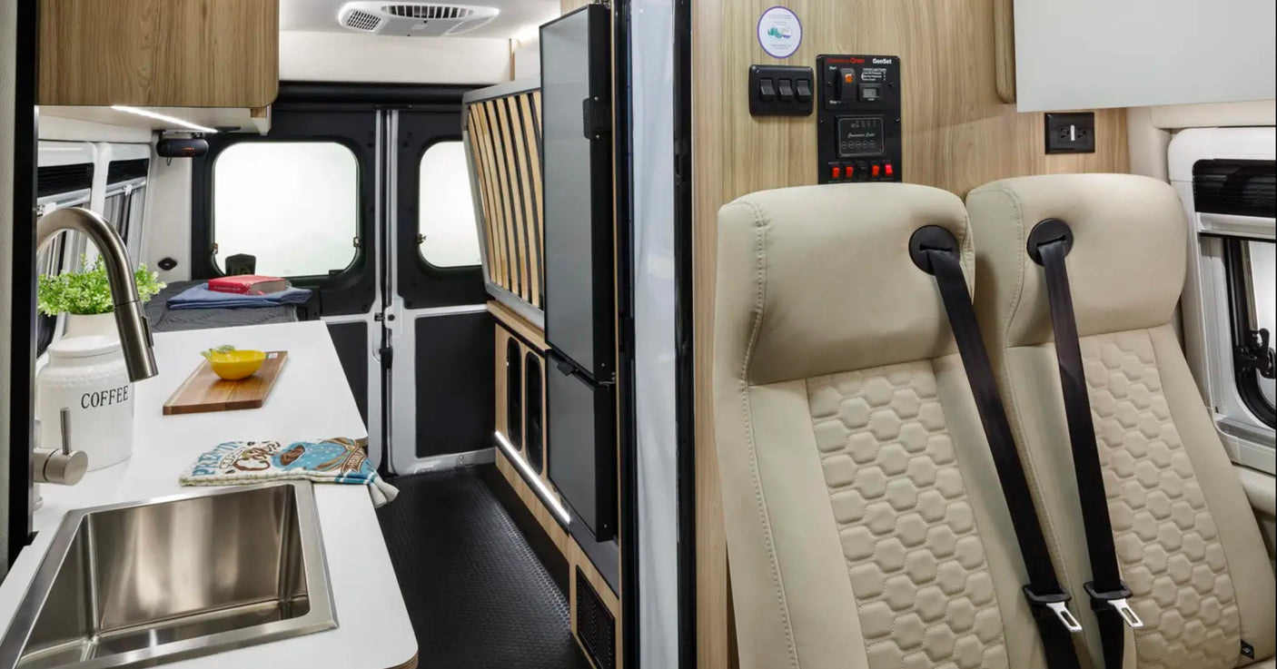 Inside a modern RV rental: a compact kitchen, bed area, and passenger seating with generator controls. Ready for travel.