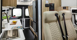 Inside a modern RV rental: a compact kitchen, bed area, and passenger seating with generator controls. Ready for travel.