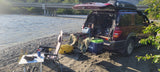 Riverside car camping setup with an SUV, offering a budget-friendly alternative to an RV rental.