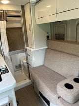 RV rental: View of modern camper interior with sofa, overhead storage, and compact wet bath.