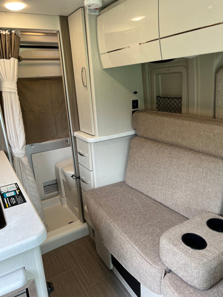 RV rental: View of modern camper interior with sofa, overhead storage, and compact wet bath.