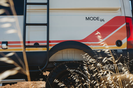 Retro-striped white MODE 4x4 camper van with ladder & off-road tires. A unique choice for your next rv rental adventure.