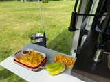 Outdoor snacks: chips, salsa, fruit, and bananas on a table next to an RV rental, enjoying nature.