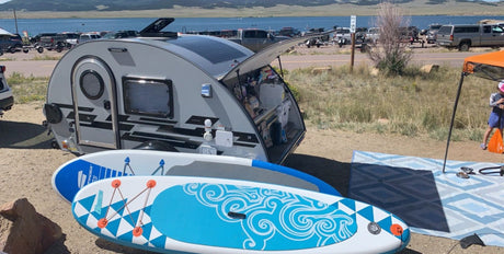 Enjoy lakeside camping with a teardrop RV rental, complete with paddleboards for water fun!